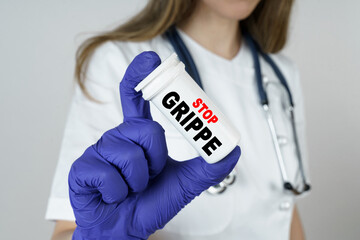 The doctor holds a medicine in his hands, which says - STOP GRIPPE