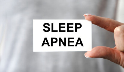 A girl holds a card with the text SLEEP APNEA.