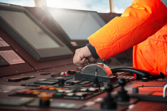 Captain crew officer hand on ship's control bridge dashboard with navigation equipment on the vessel bridge.