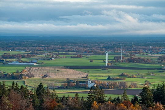 Late autumn color scene with low casting light over horizon landscape of forests and fields with windmills. Magnificent view from mountain Omberg in East of Sweden.