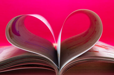 Blurry heart made from book pages over red background