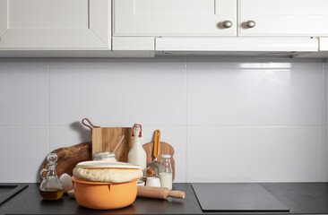 yeast dough ready for making homemade buns stands on the table among other ingredients for baking bread