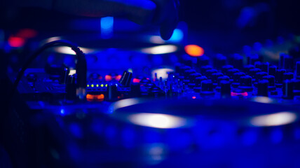 DJ controller mixer. Selective focus, blue colors, DJ hands