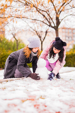 Children and young family go to play in the snow at the street. In Madrid was snow, something quite exceptional, so members of families goes to enjoy and play with snow and to do snowman in the street