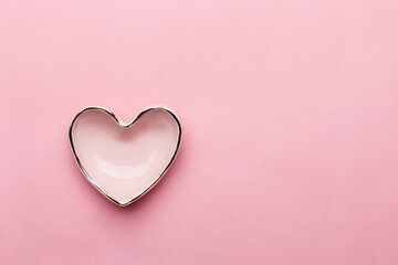Pink ceramic heart shaped bowl on pink background. Overhead view, copy space. Valentine's Day greeting card