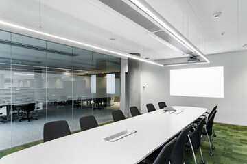 Nowoczesna sala konferencyjna w biurze korporacji, z długim stołem i ekranem na ścianie