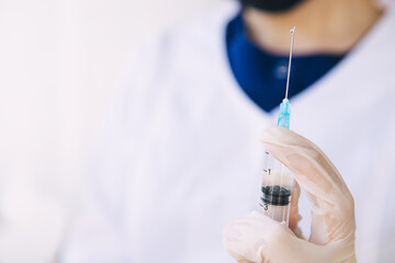 young doctor is holding a syringe of medicine. Coronavirus vaccine in a syringe. Cope space.