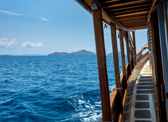 panoramic views out from a wooden cruise ship into turquoise water and an island range at the horizon in Komodo National Marine Park