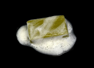 Olive Soap bar with foam isolated on black  background. Wet bar of soap. Antivirus. Coronavirus (CoV). Fighting virus.