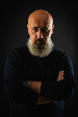 close up photo, portrait of a serious, thoughtful, bearded man on a dark background confident and dramatic looking straight. Concept of male portrait.  Low key 