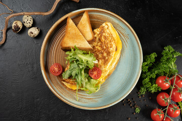 Omelet with cheese, salad and cherry tomatoes. A hot second course for breakfast of chicken eggs, cheese salad and vegetables. Classic vegetarian breakfast with toast.