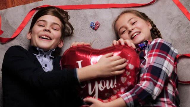little boy and girl lying on the floor with red ribbon, balloon. Concept of happy Valentine day and Brother And Sister Together Forever, Couple in Love concept. Selective focus