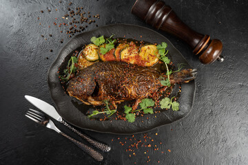 Dorada with fried zucchini. Vegetarian hot main course of sea fish and baked vegetables with microgreens and spices on a beautiful black plate.