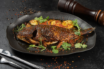 Dorada with fried zucchini. Vegetarian hot main course of sea fish and baked vegetables with microgreens and spices on a beautiful black plate.