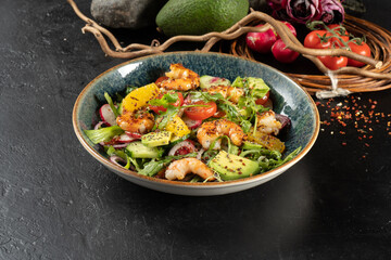 Salad with tiger prawns, avocado and orange. Cold veggie appetizer with arugula, seafood, radish, avocado, citrus, onion, cucumber and salad dressing.