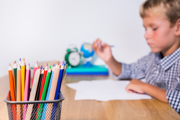 Boy, pupil sitting at the table and studying from home
