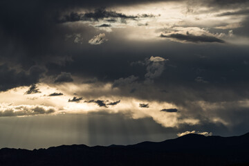 Sunbeams through clouds in a moody, stormy sky