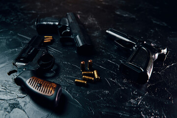 Group of pistols and bullets on black concrete table. 9mm handgun. Vintage revolver with a drum....