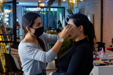 Makeup artist applies eye shadow . Beautiful latin woman with make-up faceMakeup artist applies shadow . Beautiful latin woman with make-up face