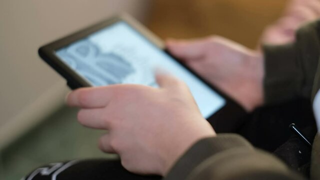 School boy kid using digital ebook reader at home,new book reading technology 