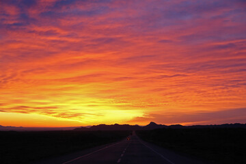 Obraz premium beautiful sun rising sky with asphalt road and cars going toward mountains in horizon