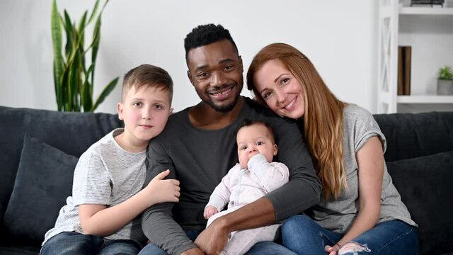 Webcam view of happy multiracial family of four. Interracial parents and kids look at camera and smiles. Video call, virtual conference, online meeting