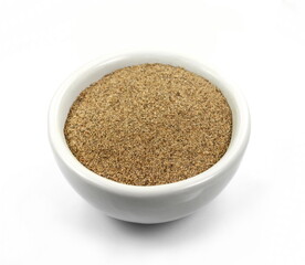 Ground carob powder (Ceratonia siliqua) in a bowl isolated on white background. Ripe carob pods and carob powder, can be used as a substitute for cocoa.