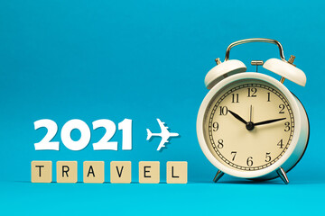 Travel trip holiday in 2021 composition and concept on blue background with word and alarm clock, copy space