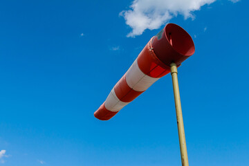 Wind speed meter, red and white stripes on blue background. Windsock indicator of wind on runway airport
