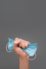 End covid-19. Coronavirus is over. Mask in fist. Victory over illness. Raised hand holding mask....