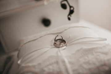 Selective focus shot of wedding rings on a white small pi