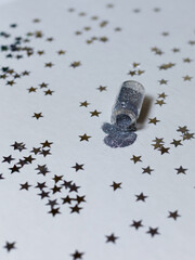 Glass bottle with silver sparkles on a white background with silver stars. Magic backdrop with glitter. Vertical frame.