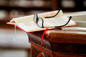 Black-framed glasses placed on top of a yellow pages holy Christian religion book