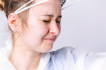 Enlarged photo. The tired doctor takes off his protective mask after a hard day at work. White background and concept of combating coronavirus.