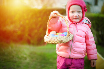 child holds basket of Easter eggs. Funny girl collected eggs..