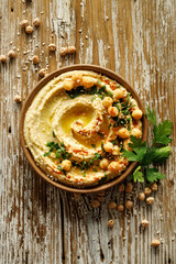 Homemade traditional hummus served on a ceramic plate on a wooden table, top view