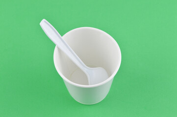 White cup with spoon isolated on a green background.