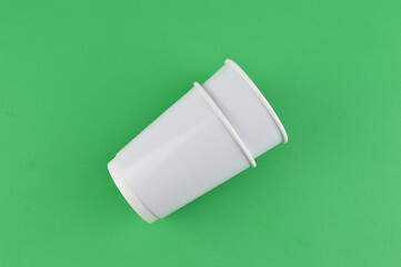 White cups isolated on a green background. 