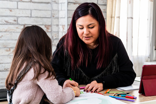 Latin woman studying with her daughter at home