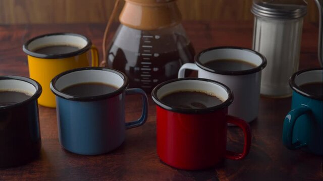 coloful enameled mug with coffee on dark wooden table
