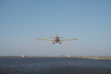 Single-engine propeller airplane flying in a perfectly clear blue sky over a calm sea © Angel Gonzalez/Wirestock
