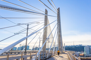 People walk over the Tilikum Crossing Bridge near sunset  in Portland,  Oregon
