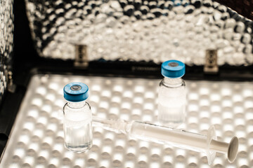 Close up on syringe with needle and vaccine injection on refrigerator illuminated - covid-19...
