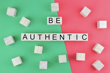 Be Authentic word made of wooden block cubes on green and red background. Business concept.
