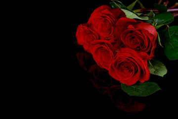 Valentines Day background with bouquet of beautiful red roses on black surface.