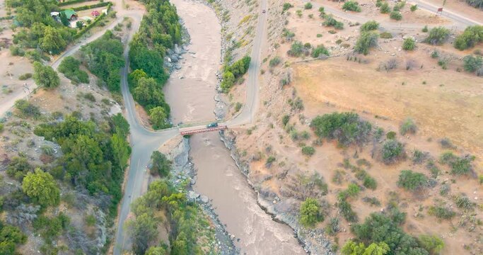 Vista a&eacute;rea del r&iacute;o Maipo en el Caj&oacute;n del Maipo cerca de Santiago de Chile con un cami&oacute;n azul pasando el puente del pueblo de El Ingenio