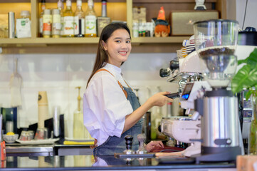 Asian women Barista smiling and using coffee machine in coffee shop counter