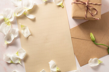 Obraz na płótnie Canvas Gift box and letter next to beautiful white flowers on pink marble background