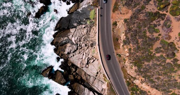 Vista de un dron con coches pasando al lado de la costa entre olas y dunas en Conc&oacute;n, Chile