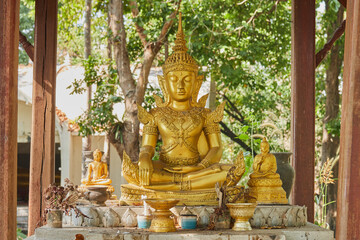 Phayao, Thailand - Dec 6, 2020: Gold God Statue in Pavilion on Green Forest Background in Wat Analayo Temple